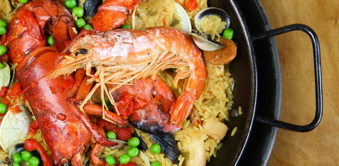 A pan of paella with shrimp, mussels, chicken, and vegetables